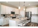 This modern kitchen features white cabinetry, stainless steel appliances, and a center island with bar stool seating at 12158 Cattleside Dr, Riverview, FL 33579