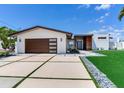 Modern home showcasing sleek lines, a stylish garage door, and manicured landscaping at 16496 Redington Dr, Redington Beach, FL 33708