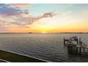 Picturesque sunset view over the water featuring a private boat dock, creating a serene and peaceful ambiance at 2402 Baywood W Dr, Dunedin, FL 34698