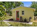 Charming yellow home exterior with a red door and inviting seating area on a brick patio at 617 Scotland St, Dunedin, FL 34698