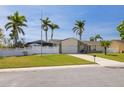 Charming single-story home featuring a lush lawn, white picket fence, and a screened-in lanai for outdoor enjoyment at 7906 Bayshore Dr, Seminole, FL 33776