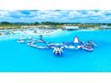 Stunning aerial view of a community waterpark with inflatable obstacle course, sandy beach, and clear blue water at 10049 Surrey Rose Dr, San Antonio, FL 33576