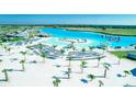Picturesque aerial showcasing white sand beach, aqua blue swimming area, palms, lounge chairs, and lakeside dining at 10049 Surrey Rose Dr, San Antonio, FL 33576