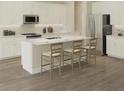 Bright kitchen features white cabinets, stainless steel appliances, and a large island with bar stool seating at 10049 Surrey Rose Dr, San Antonio, FL 33576