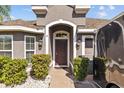 Inviting home entrance with an arched entryway, decorative lighting, and lush landscaping creating curb appeal at 14434 Scottburgh Glen Dr, Wimauma, FL 33598