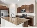 Stylish kitchen with dark cabinets, granite countertops, and stainless steel appliances at 16633 Sunburst Lake S St, Wimauma, FL 33598