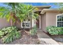 Inviting front entrance with a brick pathway and lush tropical landscaping surrounding the doorway at 1742 Oakwood Estates Dr, Plant City, FL 33563