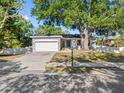 Inviting single-Gathering home with a well-manicured lawn, large tree, and a blue front door at 303 National Orange Ave, Oldsmar, FL 34677