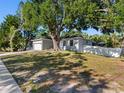 Exterior view of the home and its well-maintained yard with mature trees and white fencing at 303 National Orange Ave, Oldsmar, FL 34677