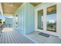 Inviting covered front porch with modern doors and stylish wood ceiling detail on a home with blue siding at 3496 Amberjack Dr, Hernando Beach, FL 34607