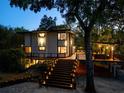 Modern two-story home at dusk with illuminated stairs and deck areas at 4701 Rambling River Rd, Brandon, FL 33511
