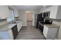 Well-lit kitchen featuring granite counters, stainless steel appliances, and white cabinets at 4750 Panorama Ave, Holiday, FL 34690