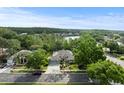 Expansive aerial view of home surrounded by lush landscaping, adjacent to a serene lake in a quiet neighborhood at 1003 Berkshire Ln, Tarpon Springs, FL 34688