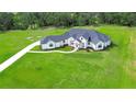 A beautiful white modern farmhouse with dark roof sits on a lush green lawn with mature trees in the background at 111 Alafia Estates Ln, Plant City, FL 33567