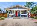 Close-up of the front of the house with a red front door and covered front porch with an American flag at 1202 E Caracas St, Tampa, FL 33603