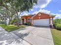 Well-maintained home featuring an attached two-car garage, manicured lawn, and mature trees at 1626 Brooksbend Dr, Wesley Chapel, FL 33543