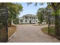 Elegant exterior view of a two-story home with lush landscaping, mature trees, gated entry, and brick circular driveway at 17062 Comunidad De Avila, Lutz, FL 33548
