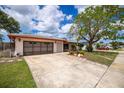 Charming single-story home featuring a well-kept lawn, mature trees and a two-car garage at 1874 Cameo Way, Clearwater, FL 33756