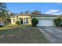A single-story home with green paint, a well-manicured lawn, and an attached two-car garage at 3545 E Lake Dr, Land O Lakes, FL 34639