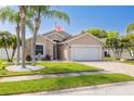 Charming home with a manicured lawn, decorative palm trees, brick driveway, and an American flag at 384 Tavernier Cir, Oldsmar, FL 34677
