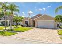 Charming home with a manicured lawn, decorative palm trees, brick driveway, and an American flag at 384 Tavernier Cir, Oldsmar, FL 34677