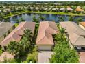 Aerial view of a home near a lake with a well-maintained backyard and tile roof at 4811 Sandy Glen Way, Wimauma, FL 33598