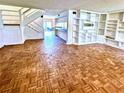 Open living room featuring unique parquet flooring, built-in shelves, and staircase access at 5454 Saddlebrook Way # 2, Wesley Chapel, FL 33543