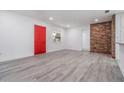 Bright and airy living room with brick accent wall and new flooring with a red door in the corner at 7249 Berry Rd, Zephyrhills, FL 33540