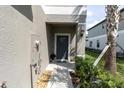 Covered front entry featuring a gray front door and manicured landscaping at 8299 Crescent Oaks Dr, New Port Richey, FL 34655