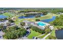 Stunning aerial view showcasing the community's golf course, clubhouse, pool, and scenic water features at 9608 Rolling Cir, San Antonio, FL 33576