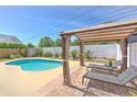 Backyard oasis featuring a pool, covered pergola, lounge chairs, and privacy fencing at 1666 Meadow Oak Ln, Tarpon Springs, FL 34689
