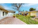 Beautiful backyard with brick pavers, lush landscaping, and water views from the covered patio at 179 Bath Club N Blvd, North Redington Beach, FL 33708