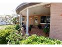 Charming front porch with a colorful brick-style floor, seating, and manicured landscaping at 3302 Eisenhower Dr, Holiday, FL 34691