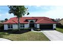 Charming single-story home with a red tile roof, arched entry, and lush landscaping for enhanced curb appeal at 4804 Longwater Way, Tampa, FL 33615