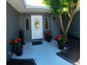 Welcoming front entry with decorative door, potted flowers and mature landscaping accents at 7504 Lily Pad Ct, Hudson, FL 34667