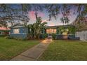 Charming blue home with well-manicured lawn, lush landscaping, and a welcoming walkway at sunset at 818 37Th Ne Ave, St Petersburg, FL 33704