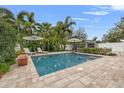 Inviting backyard pool area with pavers, lounge chairs, umbrellas, and lush tropical landscaping for relaxation and enjoyment at 818 37Th Ne Ave, St Petersburg, FL 33704