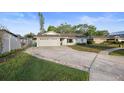Single-story home featuring a long driveway, well-manicured lawn, white garage, and a charming pastel pink front door at 10812 96Th St, Largo, FL 33773