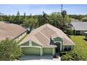 Aerial view of the green home featuring a spacious three-car garage and lush landscaping by the water at 1211 Penny Ct, Dunedin, FL 34698