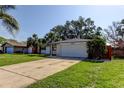 Beautiful home featuring a well-maintained lawn, an expansive driveway, and attached garage at 2131 Cedar Dr, Dunedin, FL 34698