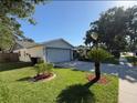 Spacious driveway leading to a two-car garage, complemented by a lush green lawn and mature landscaping at 5814 Silver Moon Ave, Tampa, FL 33625
