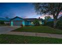 Charming light-blue house featuring a well-maintained lawn and a gray two-car garage at dusk at 8742 Bermuda Ln, Port Richey, FL 34668