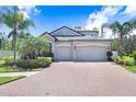 Stunning two-story home with a brick driveway, lush landscaping, and a spacious three-car garage at 10703 Morning Dew Way, Tampa, FL 33647