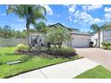 Attractive home featuring a lush lawn, mature palms, and a convenient two-car garage at 10703 Morning Dew Way, Tampa, FL 33647