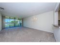 Sunlit living room with plush carpet, chandelier, and sliding doors to private balcony at 1805 Mariner Dr # 52, Tarpon Springs, FL 34689