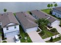 Aerial view of homes with well-maintained lawns, driveways, and a picturesque lake in the background at 20983 Monza Loop, Land O Lakes, FL 34638