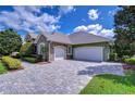 Paver driveway leads to a two-car and one-car garage, surrounded by mature landscaping at 22338 Bartholdi Cir, Land O Lakes, FL 34639