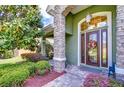 Charming front door with stone column and colorful wreath surrounded by colorful landscaping at 22338 Bartholdi Cir, Land O Lakes, FL 34639