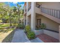 Townhouse entrance with stairs to upper level, brick landing, and mature landscaping at 3016 Landmark Blvd # 401, Palm Harbor, FL 34684