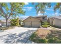 Townhouse exterior featuring a two-car garage, neutral paint, and mature trees at 3016 Landmark Blvd # 401, Palm Harbor, FL 34684
